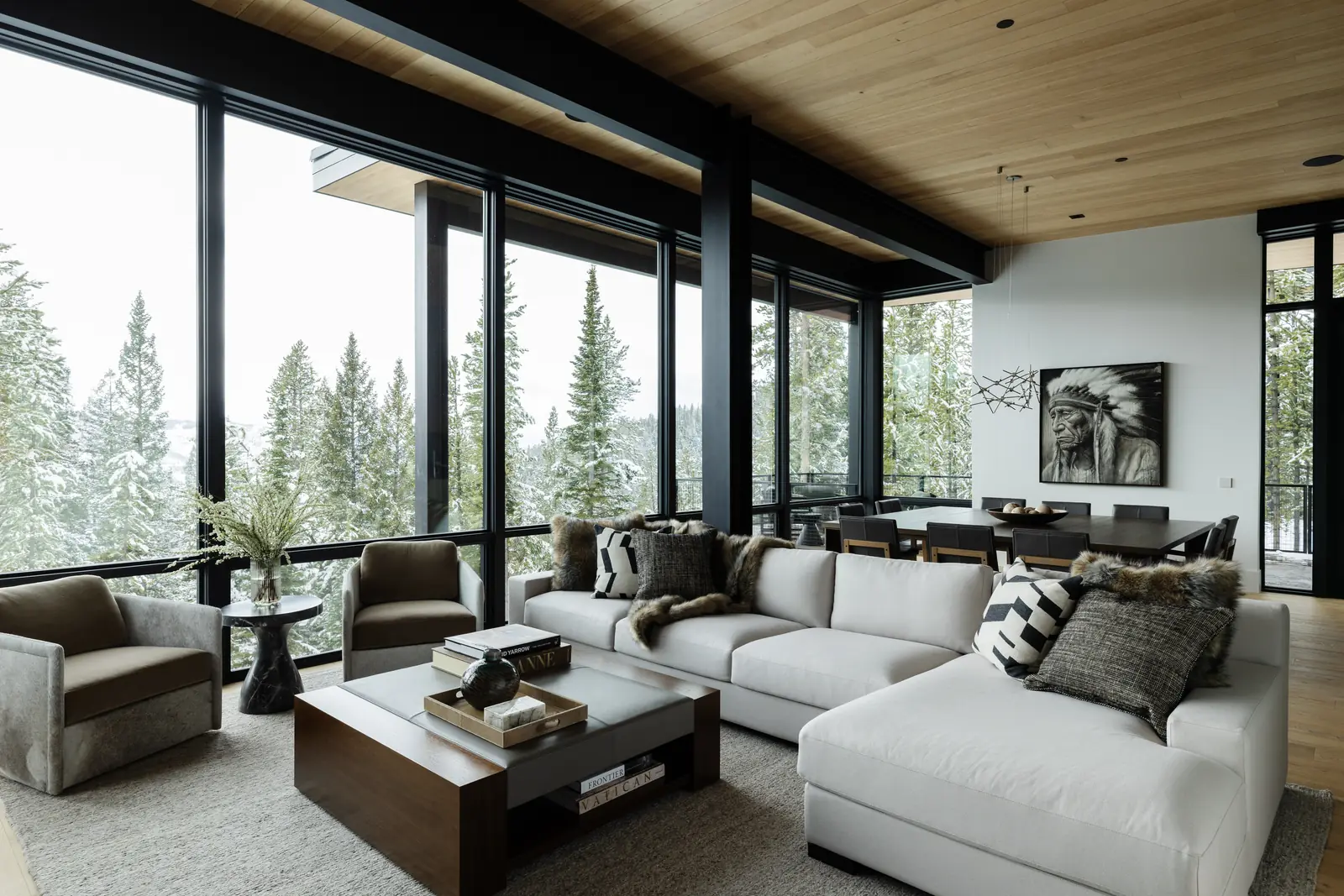 Living room with walls of glass onto snowy firs under a cedar ceiling