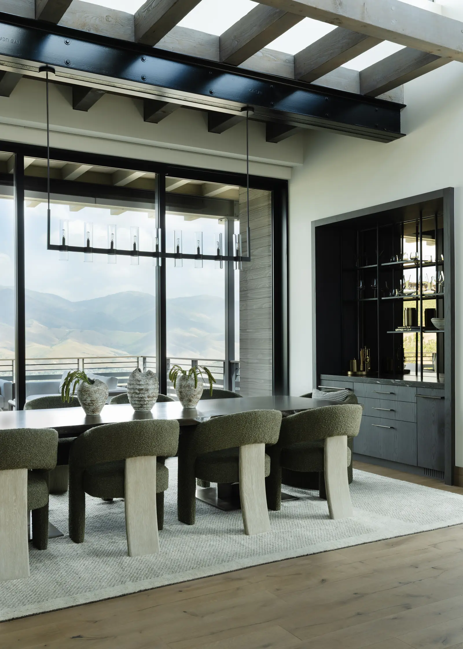 Dining room under a linear chandelier, with views to the mountains