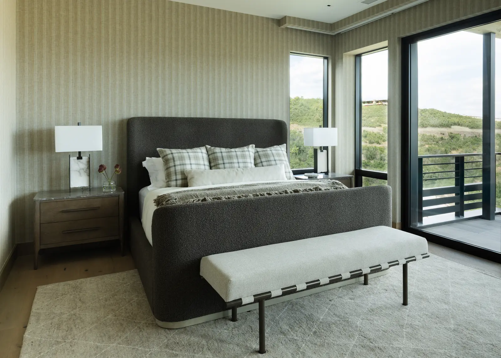 Bedroom with a charcoal upholstered bed, plaid pillows and doors to the deck